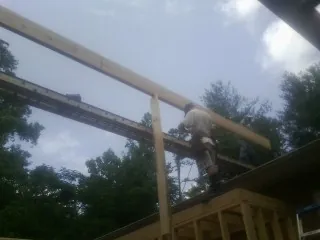 Carpenter setting a ridge beam over a new addition frame — Ice Dam Removal by Roofing Brothers in Coalport
