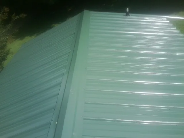 New green metal panels meeting at the ridge of a roof — Flat Roof Repair work by our crew in Coalport