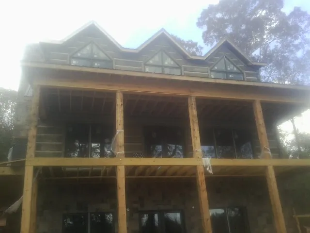 Dormers and porch framing on a large log home under construction — Roof Coating work by our crew in Coalport