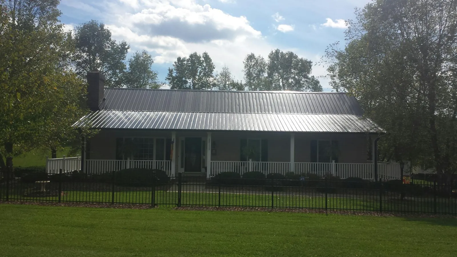 Gray metal roof on a brick ranch with a full width front porch — Gutter Guard Installation work by our crew in Coalport