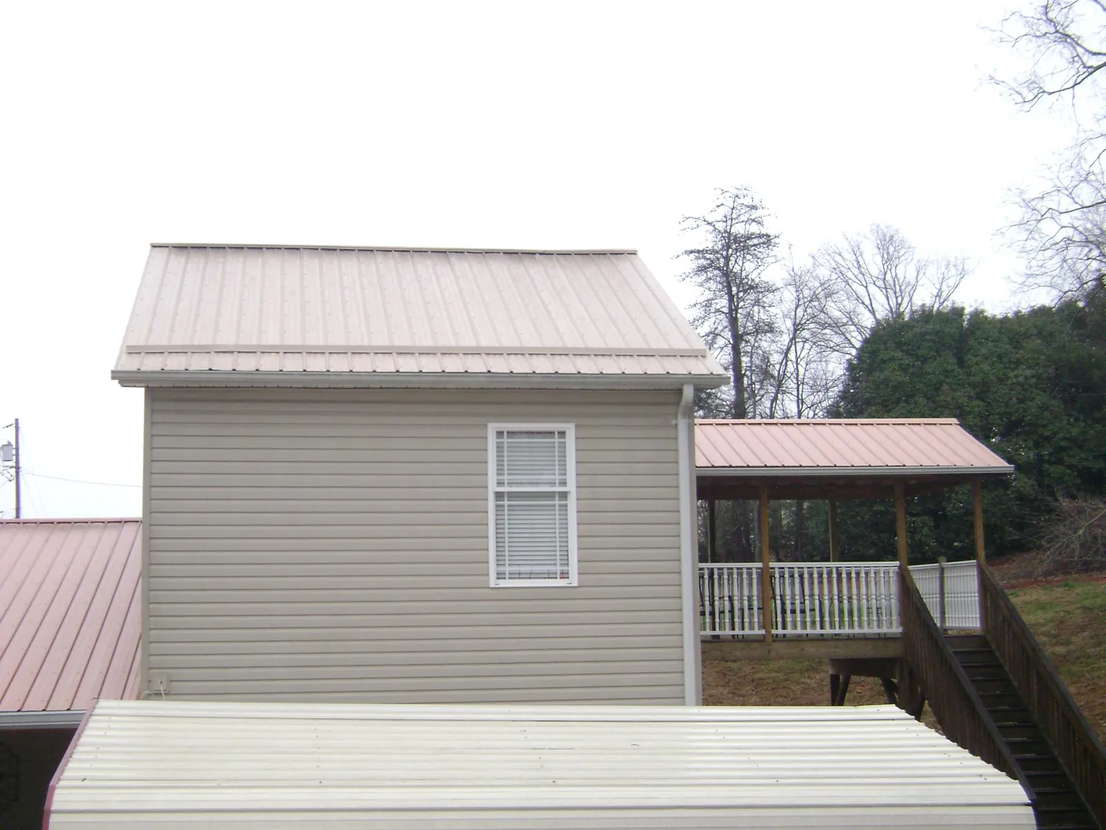 Tan metal roofs on a two story addition and attached porch, from a Roof Replacement job in Coalport