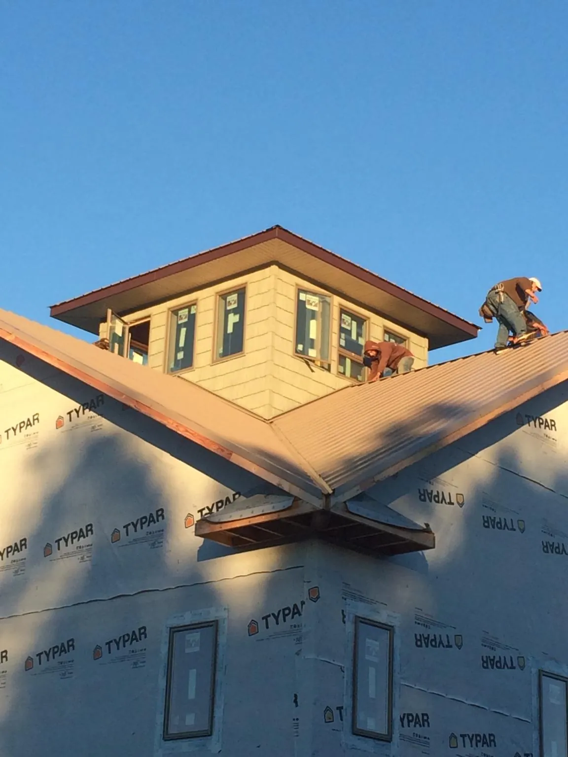Roofers working around a rooftop cupola on a new metal roof at sunset — Roof Waterproofing in Coalport by Roofing Brothers